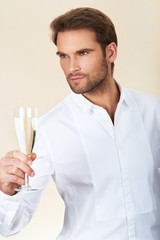 Handsome man in white shirt celebrating with glass of champagne