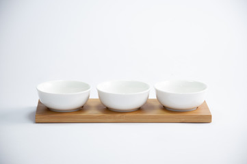 trio of white coffee cups arranged in a row on a wooden tray