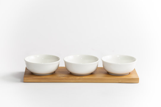 trio of white coffee cups arranged in a row on a wooden tray