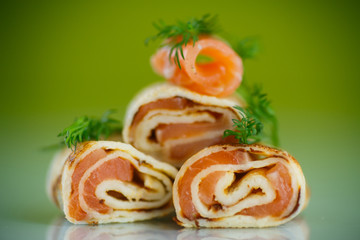 Obraz na płótnie Canvas rolls of thin pancakes with salted red fish