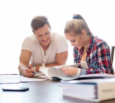 Young students couple preparing for exams behind table