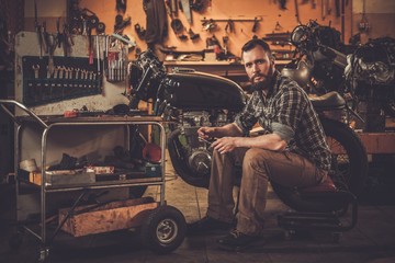 Mechanic with cafe-racer motorcycle  in custom garage