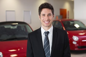 Smiling businessman standing beside a car