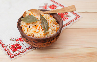 sauerkraut in ceramic bowl with wooden spoon on wooden table wit