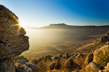 sunbeam shining above stone in mountains at sunset