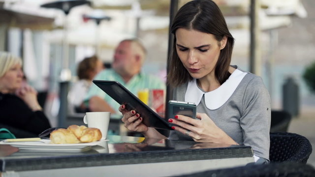 businesswoman comparing data on tablet computer and smartphone