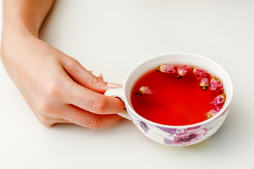 hands that hold a cup of tea from the flowers of roses