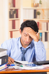 young stressed overwhelmed man with piles of folders on his desk