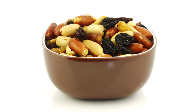 Mixed Peanuts And Raisins In A Brown Bowl On A White Background