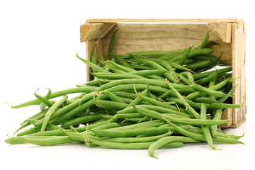 bunch of green beans in a wooden box on a white background