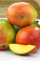 Fototapeta na wymiar mango fruit and a cut one in a wooden box on a white background