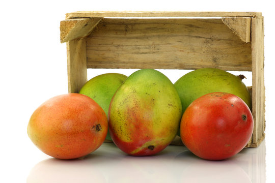 mango fruit and a cut one in a wooden box on a white background