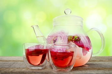 Exotic red tea with flowers in glass teapot and cup