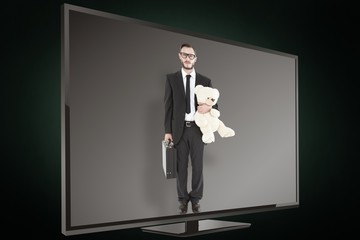 Composite image of geeky businessman holding briefcase and teddy