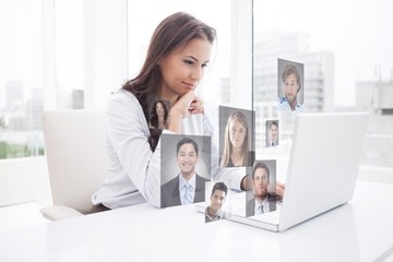 Composite image of happy businesswoman using laptop at her desk