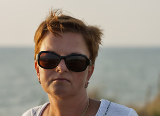 sunset portrait of tanned middle age woman in sunglasses