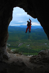 Спелеолог спускается по веревке в пещеру