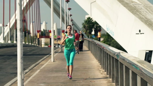 Young woman jogging on bridge in the city, slow motion