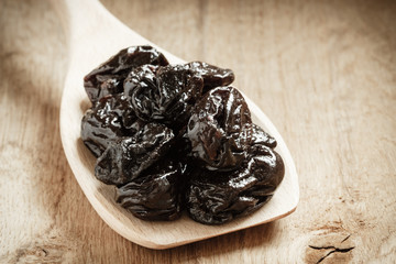 dried plums prunes on wooden spoon