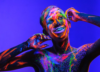 Man covered with fluorescent paint on color background