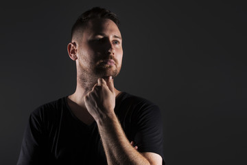 Fototapeta premium Man posing with dark background and hard lighting