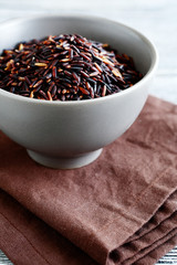 Black rice in a clay bowl on napkin