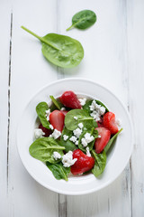 Salad with strawberries, spinach leaves and cheese, above view