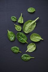 Above view of spinach leaves over black wooden surface