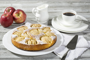 Apfelkuchen, Kaffeetasse und Teller, Äpfel auf Holz
