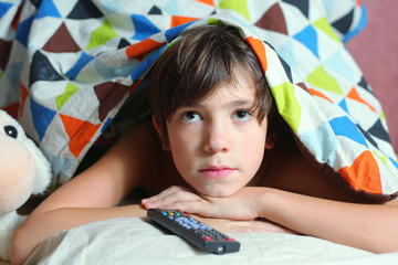 preteen handsome boy have a good time in bed watch tv