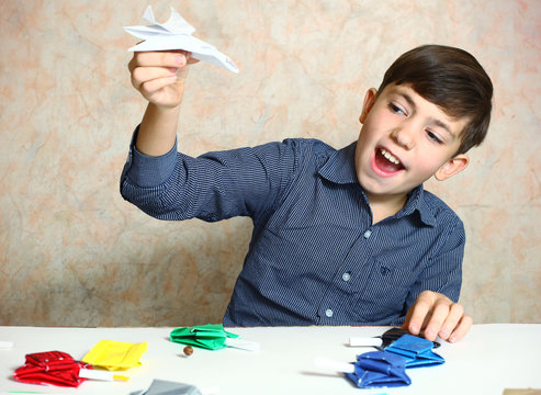 creative handsome preteen boy make origami tanks and plain  from
