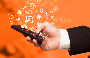 Hand holding smartphone with media icons and symbol