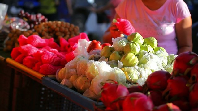 Woman chooses fruits at an open-air market in Koh Samui Thailand
