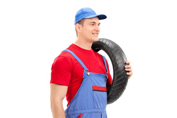 Mechanic carrying a tire and walking