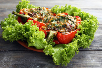 Stuffed red peppers with greens on plate on wooden table