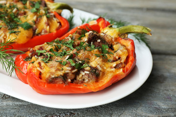 Stuffed red peppers with greens on plate on wooden table