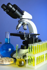 Microscope, grains and test tubes on table, on color background