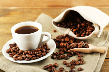 Cup of coffee with beans on rustic wooden background