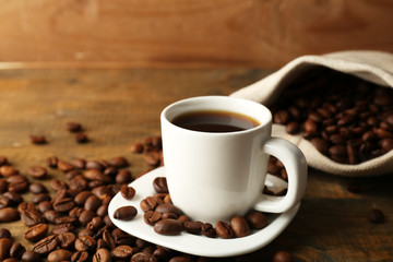 Cup of coffee with beans on rustic wooden background