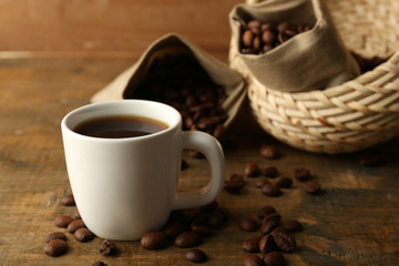 Cup of coffee with beans on rustic wooden background