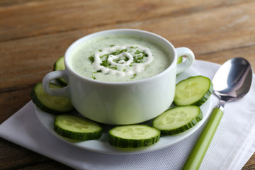 Cucumber soup in bowl on rustic wooden table background