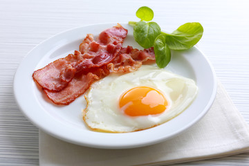 Bacon and eggs on color wooden table background
