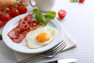 Bacon and eggs on color wooden table background