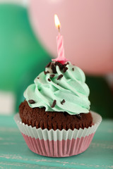 Delicious birthday cupcake on table on bright background