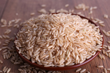 Brown rice on plate on wooden background