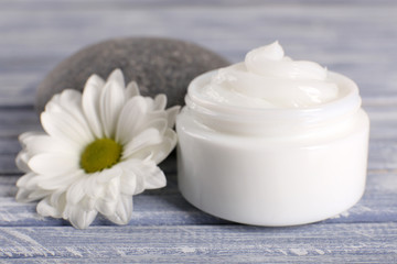 Obraz na płótnie Canvas Cosmetic cream with spa stones and chamomile