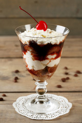 Tasty tiramisu dessert in glass, on wooden background