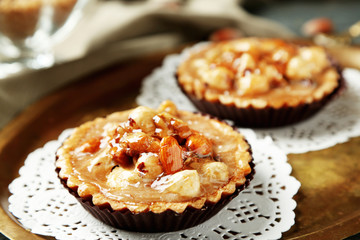 Mini cakes with nuts on napkin on wooden background