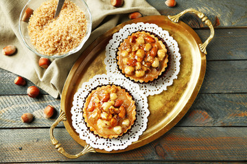 Mini cakes with nuts on napkin on wooden background