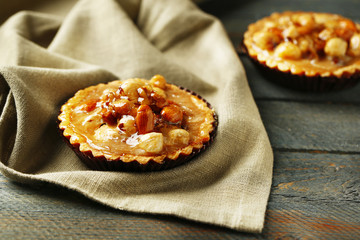 Mini cakes with nuts on napkin on wooden background